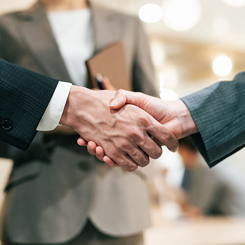 不動産売却の交渉が成立して握手するスタッフ